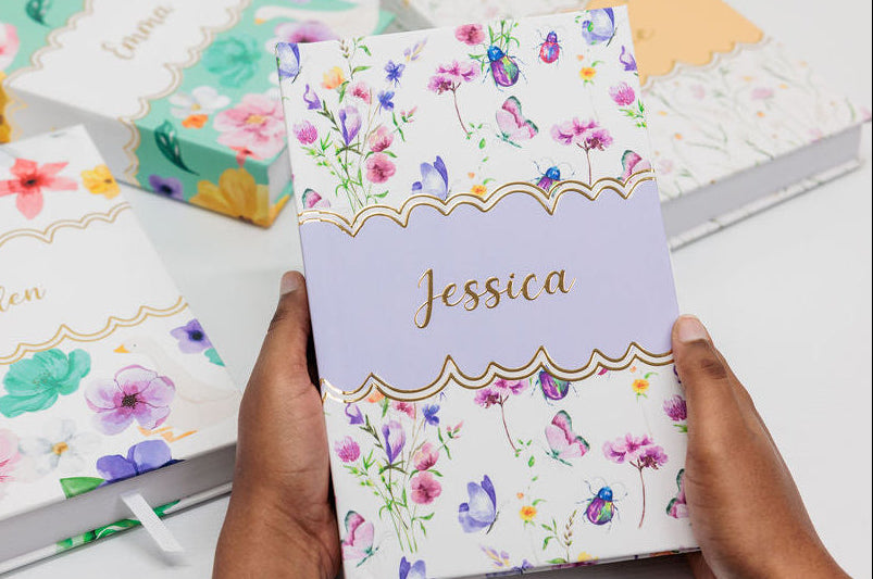 Floral-themed notebooks with personalized names on a white surface